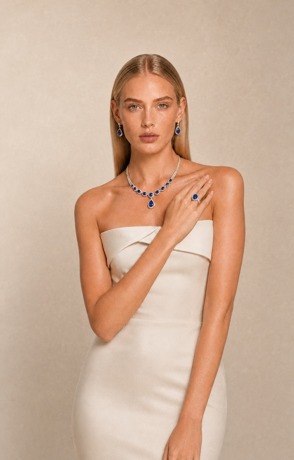 Ministry of Gems model in an ivory gown wearing blue sapphire and diamond statement jewellery against pale limestone.
